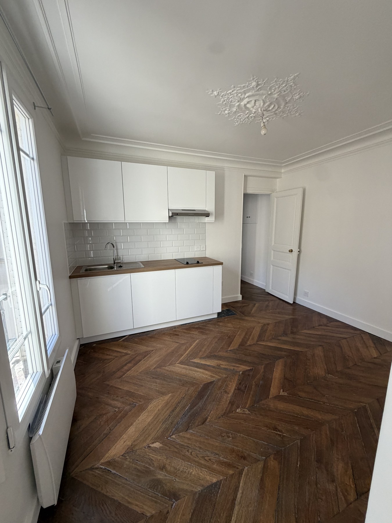 Séjour parqueté avec cuisine ouverte de l’appartement rue Fondary